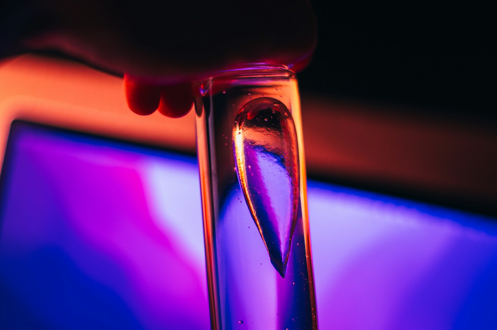 a close up of a person holding a glass in front of a computer screen